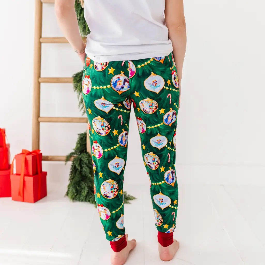 Person wearing festive green pajama pants with Christmas-themed designs in a home setting.