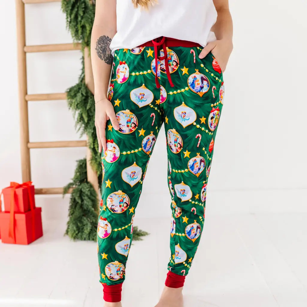 Person wearing festive green pajama pants with Christmas-themed design on a white background.