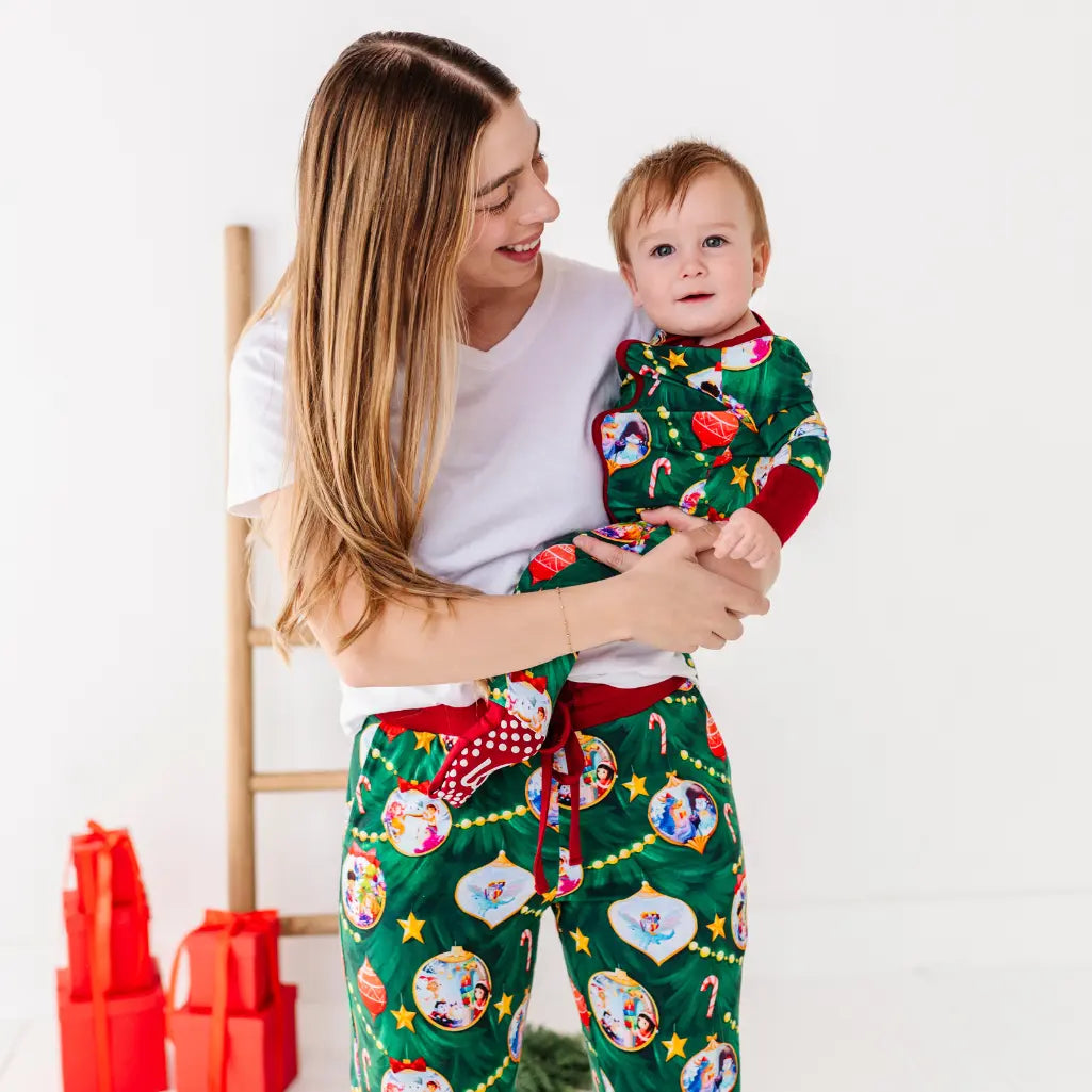Woman holding a child wearing matching Christmas pajamas with a white background
