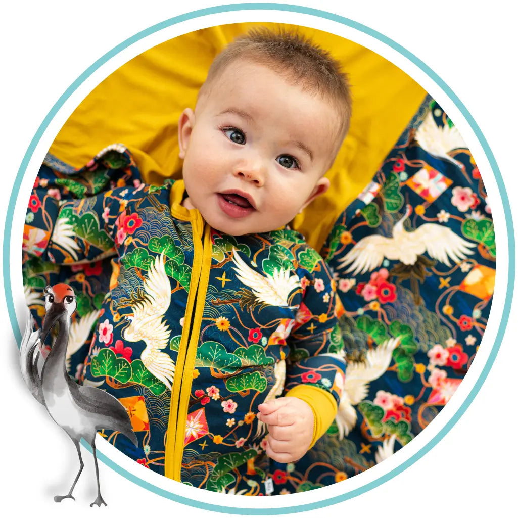 Baby wearing a colorful jacket with bird patterns and a yellow interior.