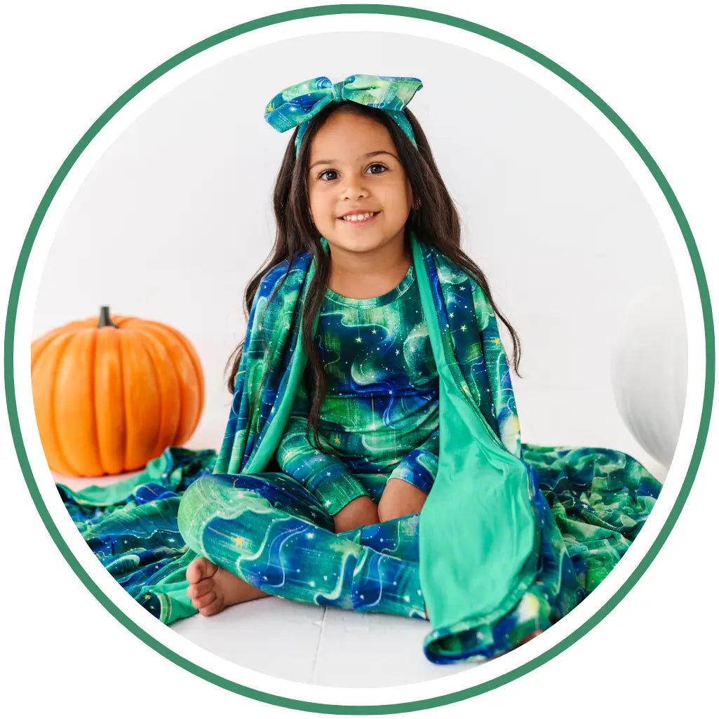Child in a green and blue costume with a pumpkin on a white background