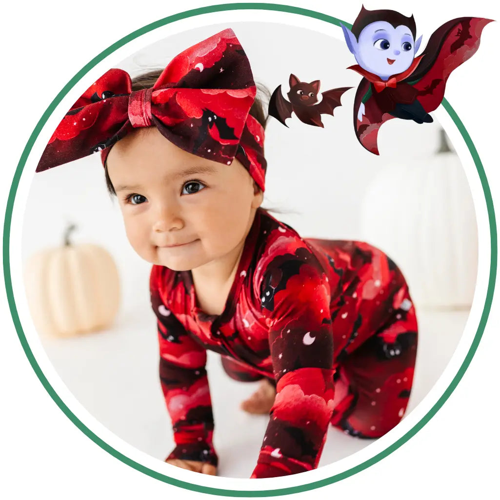 Baby in red and black Halloween-themed outfit with a large bow and bat design.