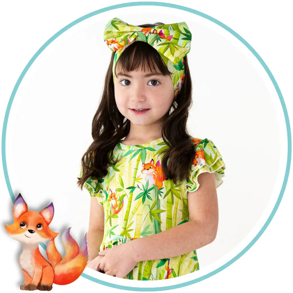 Child wearing a colorful shirt with fox designs and a headband, surrounded by fox illustrations.