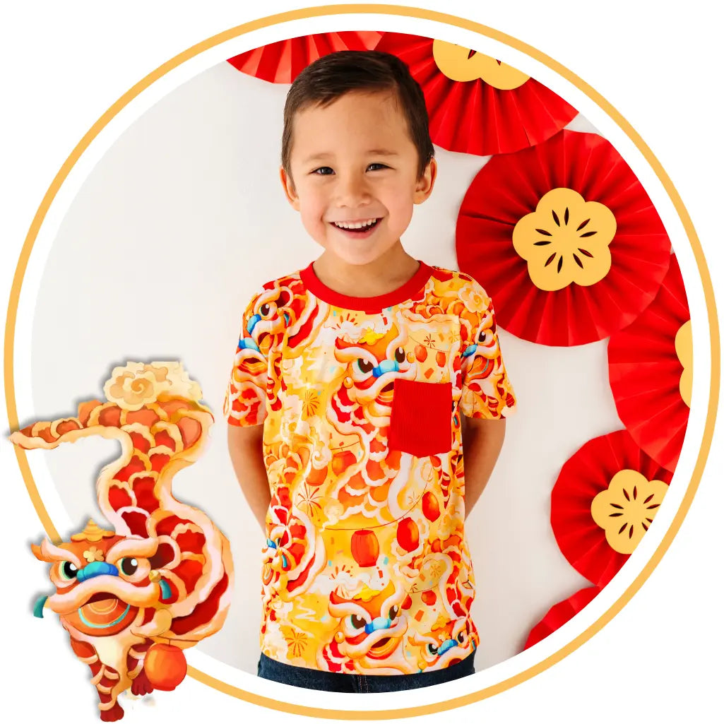 Child wearing a colorful shirt with dragon design, surrounded by red and gold decorations.