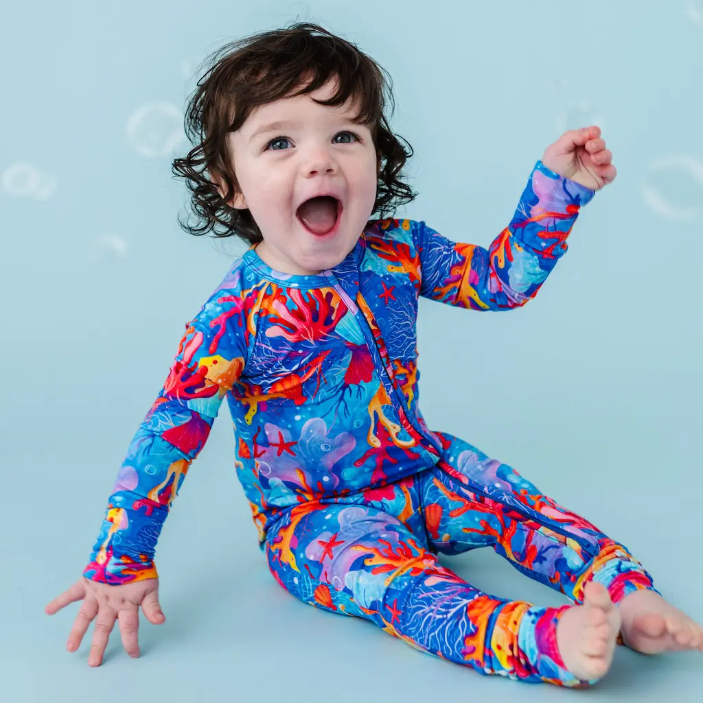 Child wearing a colorful ocean-themed swimsuit on a blue background.