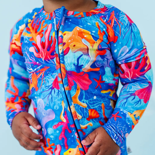 Colorful coral reef-themed jacket on a child against a light blue background