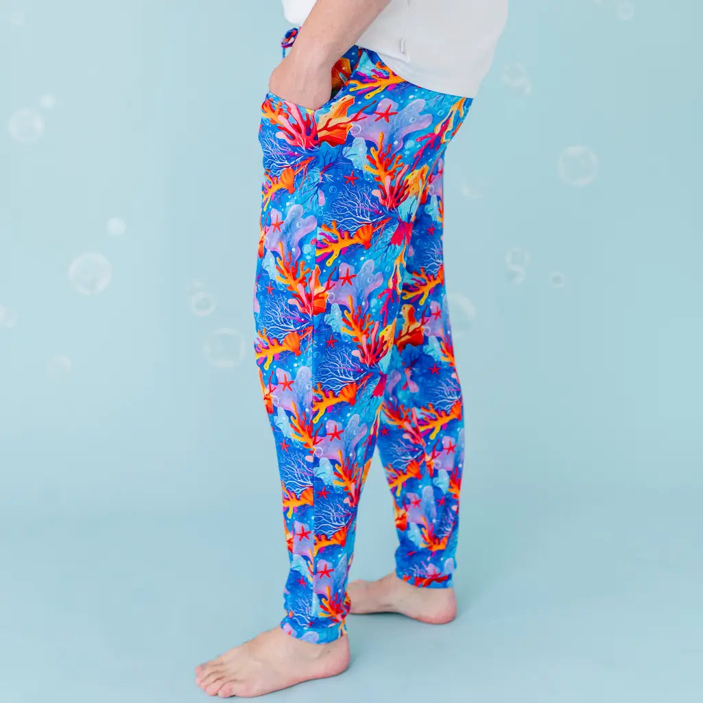 Colorful coral reef patterned leggings worn by a person on a light blue background.