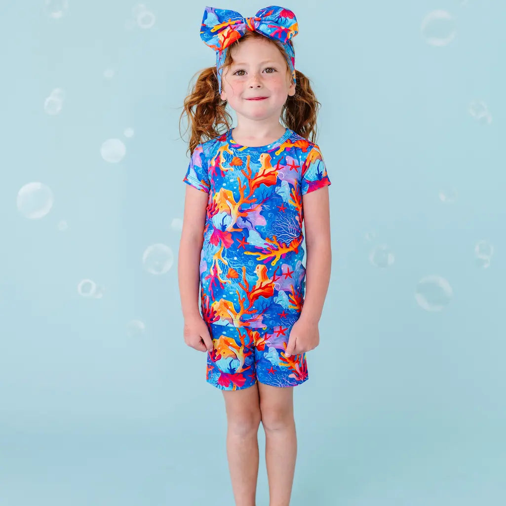 Child wearing a colorful coral dress on a blue background with bubbles.