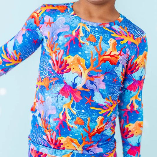 Colorful coral-themed long-sleeve shirt on a light blue background