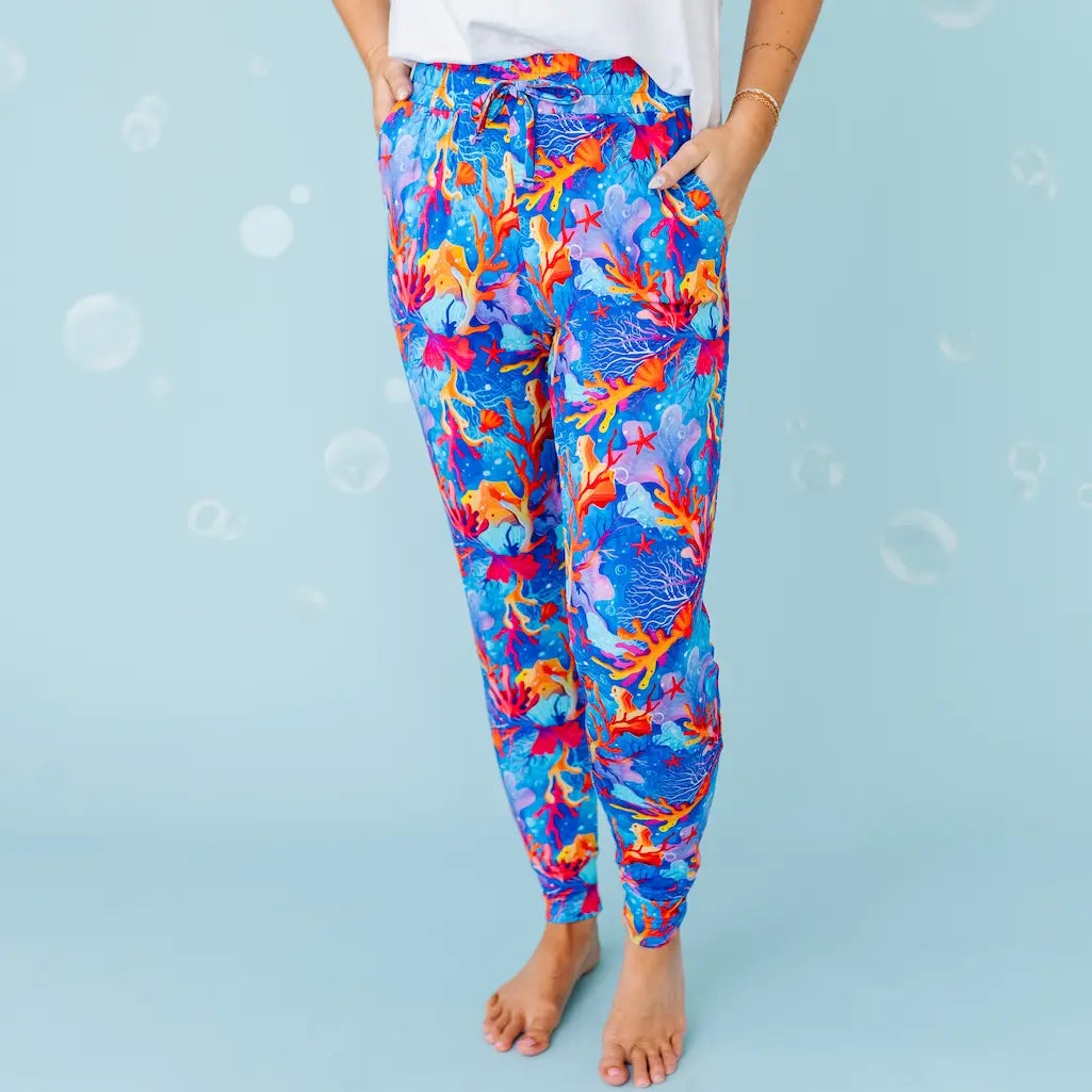 Colorful coral reef-patterned leggings worn by a person on a light blue background.