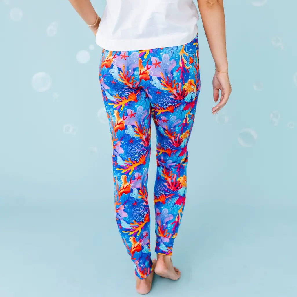 Colorful coral reef-patterned leggings worn by a person on a light blue background.
