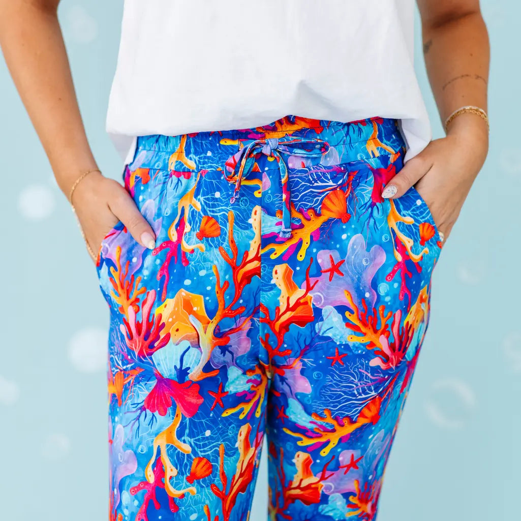 Colorful coral patterned pants worn by a person with a light blue background.