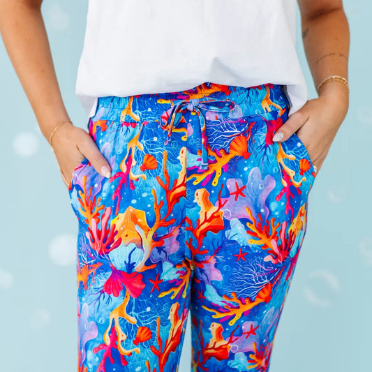 Colorful coral patterned pants worn by a person with a light blue background.