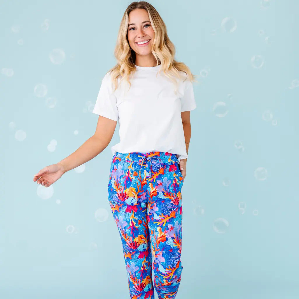 Woman wearing a white t-shirt and colorful pants on a light blue background
