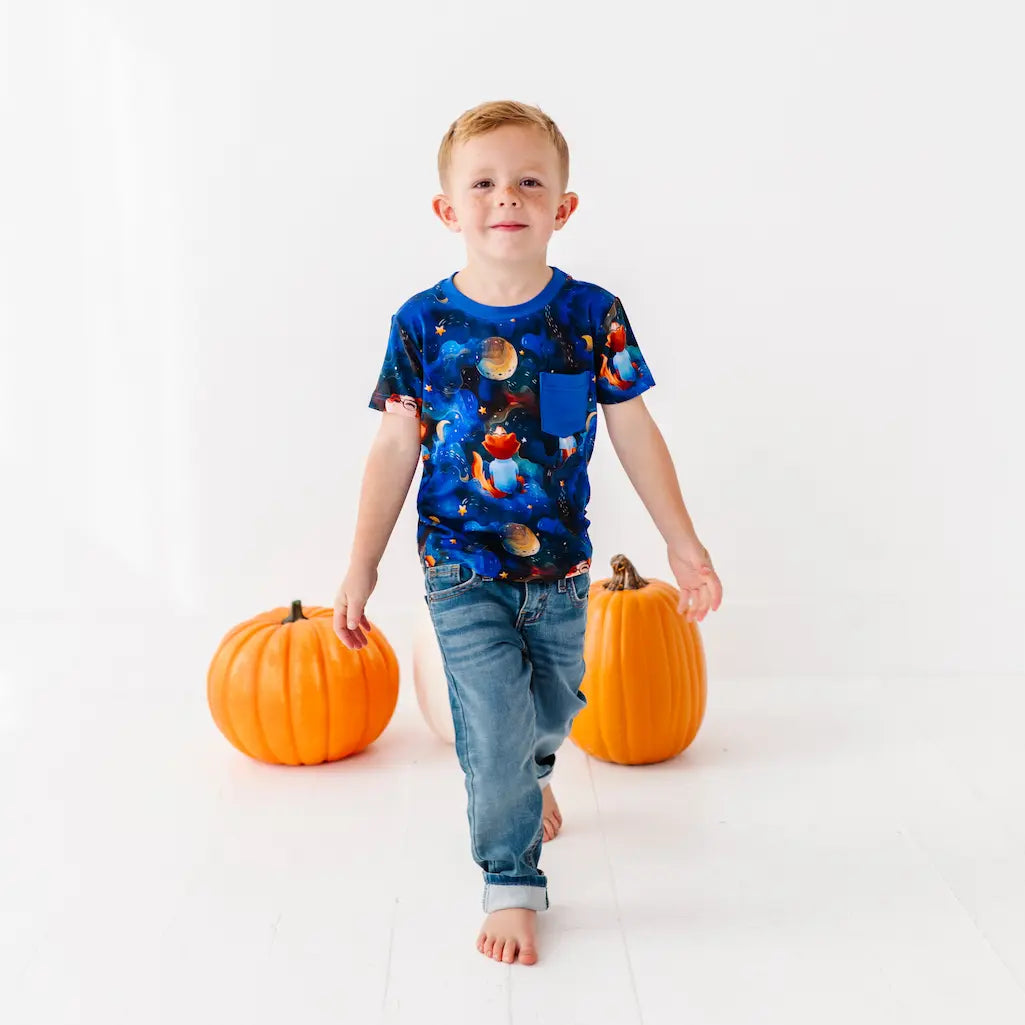 Child wearing a space-themed shirt with two pumpkins on a white background