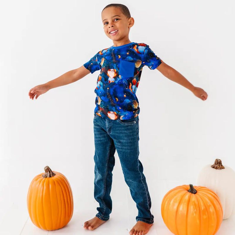 Child wearing a colorful shirt and jeans standing between pumpkins on a white background