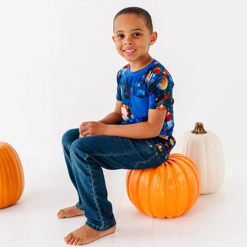 Child sitting on a pumpkin with pumpkins around on a white background