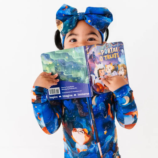 Child wearing a blue costume with animal designs, holding two books, on a white background