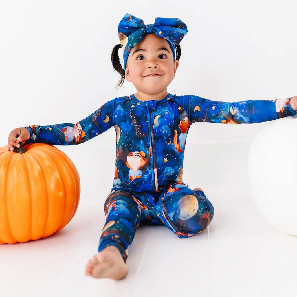 Child wearing a space-themed onesie with a pumpkin on a white background
