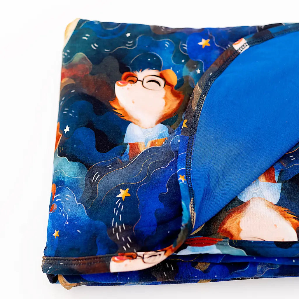 Colorful folded blanket featuring a whimsical cartoon character in a starry night design