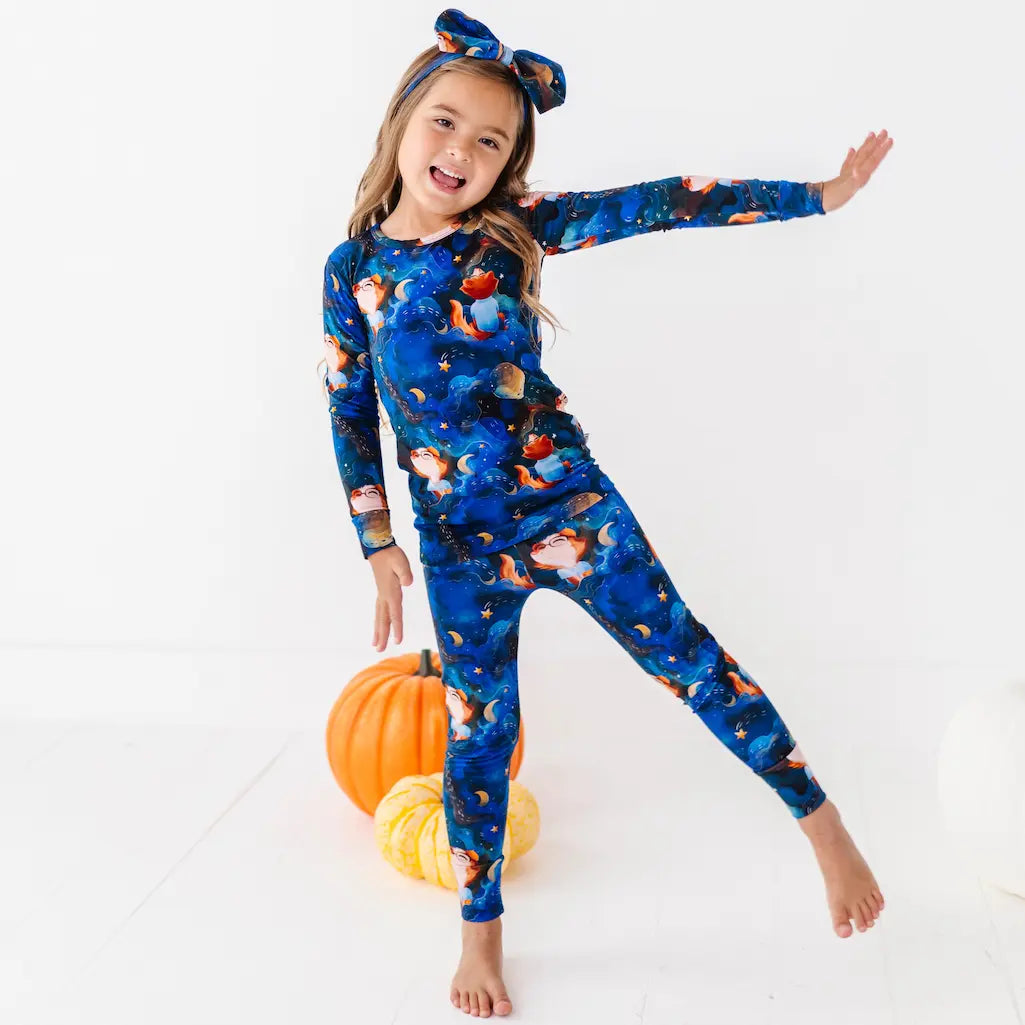 Child wearing a blue Halloween-themed onesie with pumpkins and ghosts on a white background.