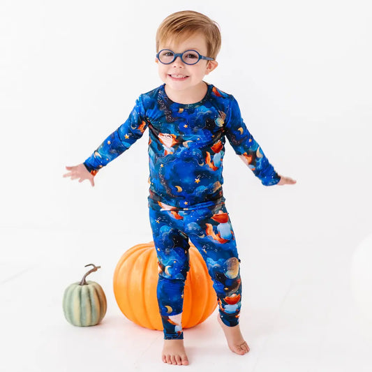 Child wearing a blue space-themed onesie with pumpkins on a white background