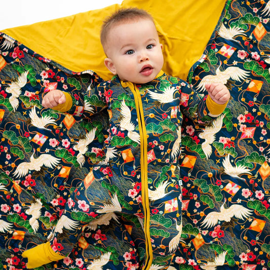 Baby in a colorful floral and bird patterned outfit with yellow interior