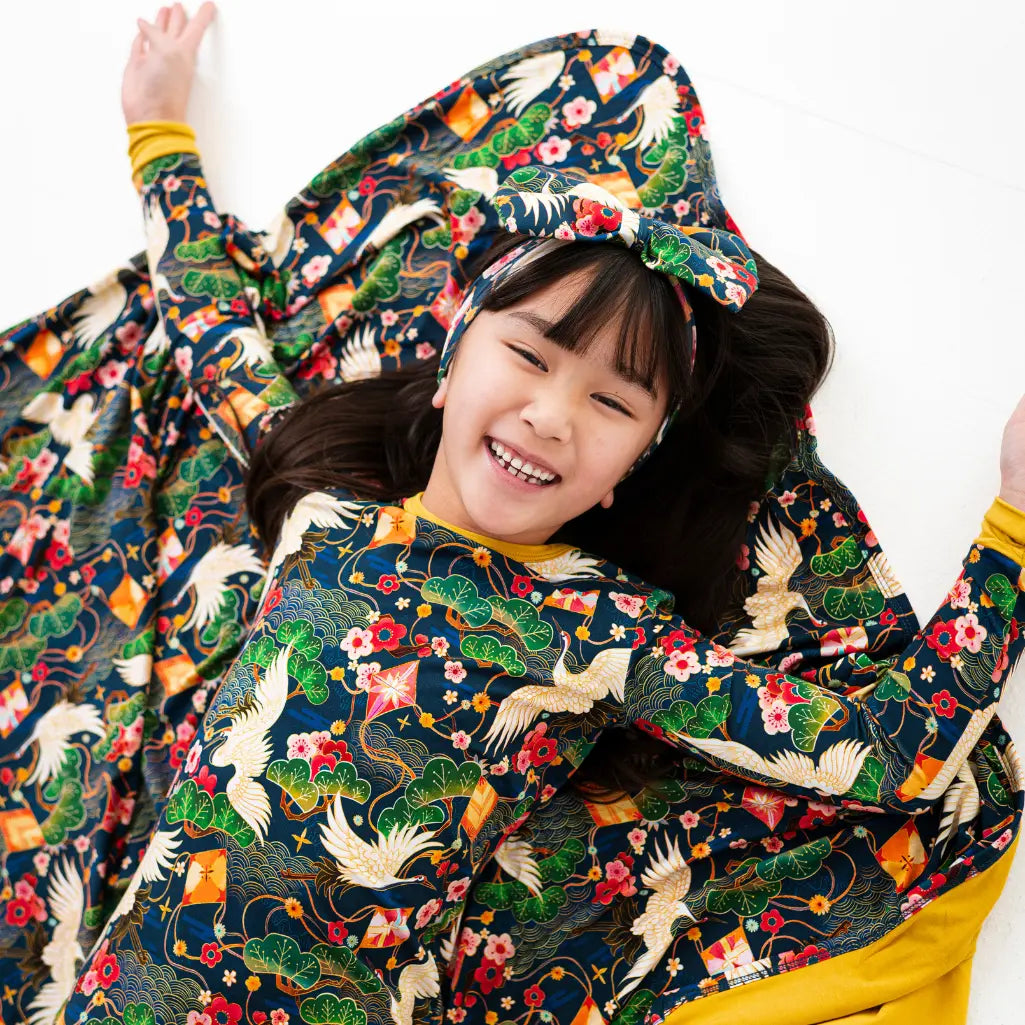 Child wearing a colorful traditional garment with floral and animal patterns on a white background