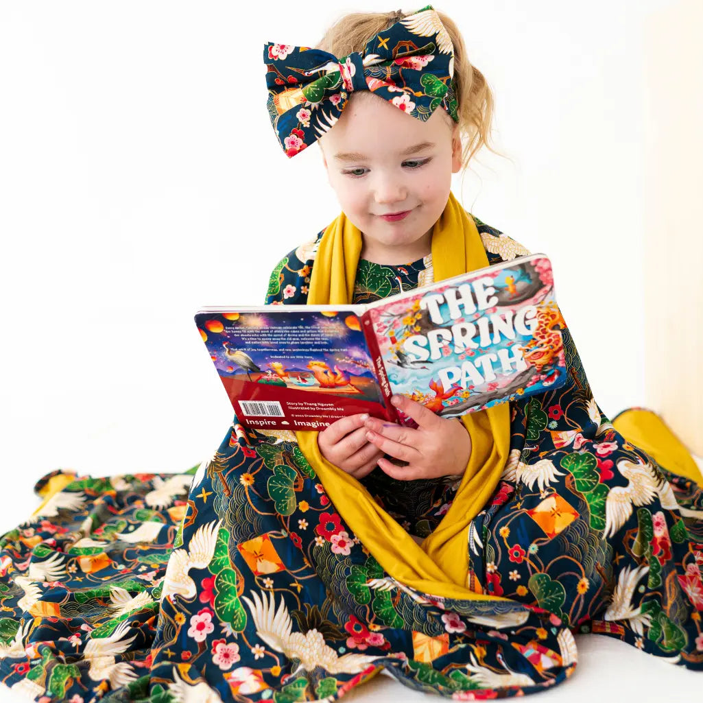 Child in a colorful outfit holding a book titled 'The Spring Path' on a white background