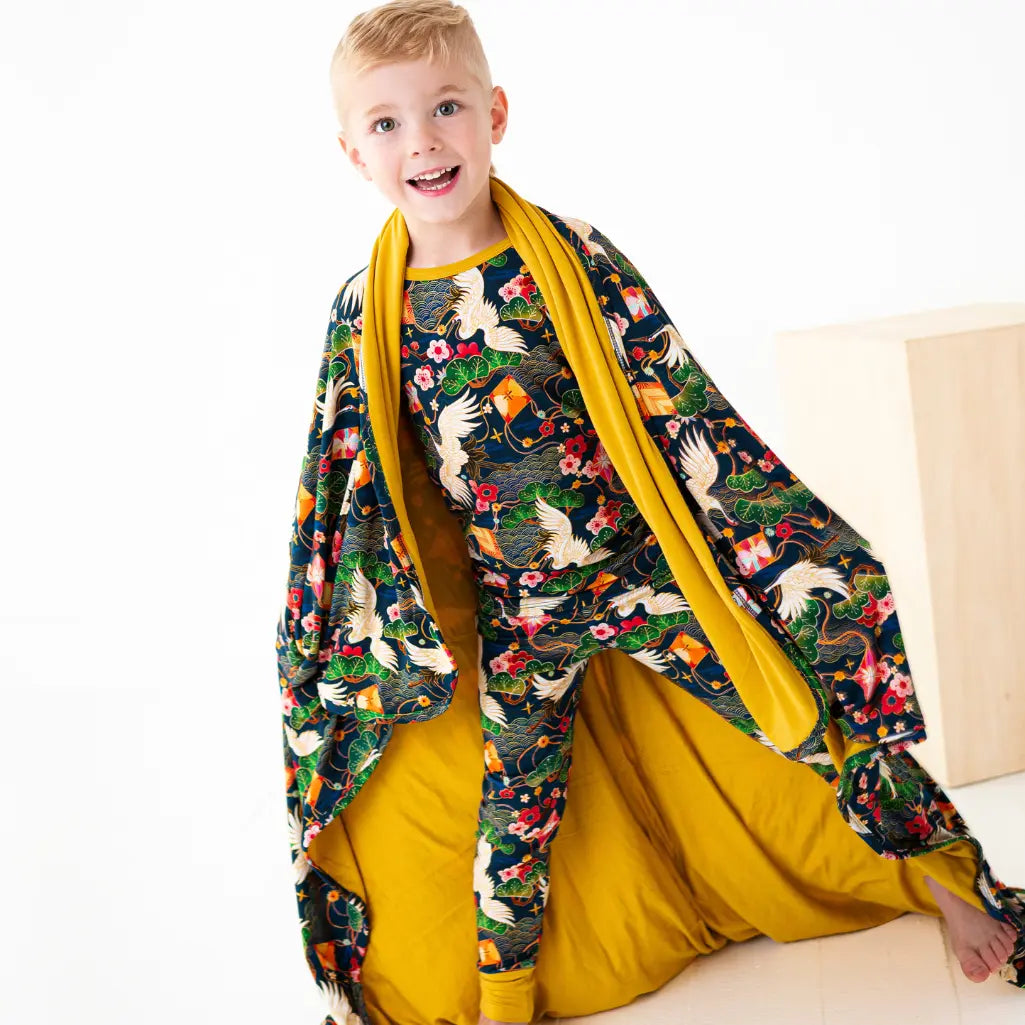 Child wearing a colorful floral-patterned shawl over a yellow outfit on a white background