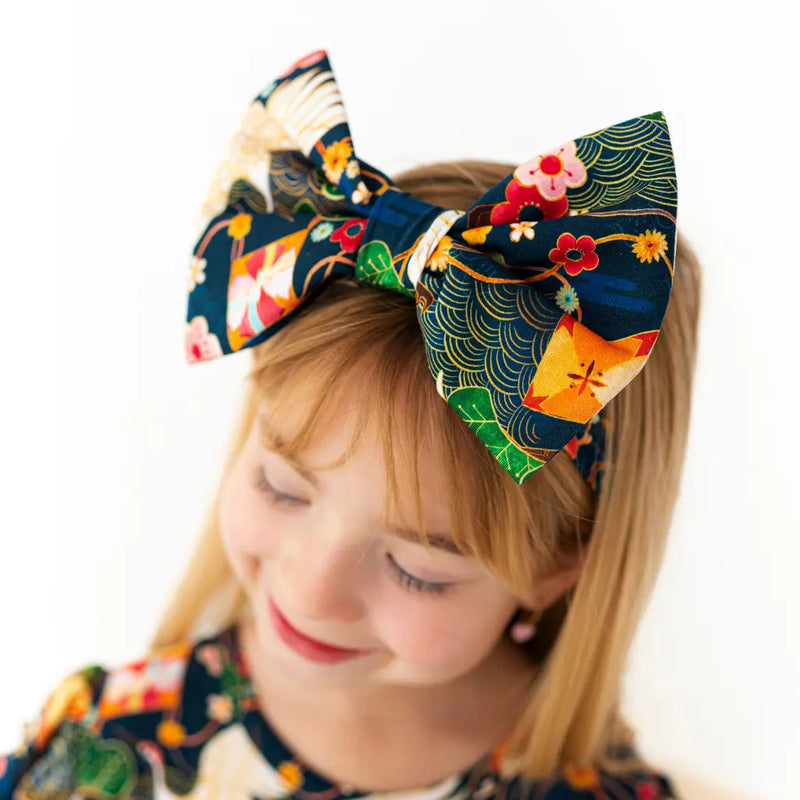 Child wearing a colorful headband with a large bow on a white background