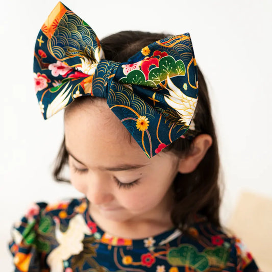 Child wearing a colorful headband with floral and leaf patterns on a white background