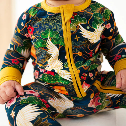 Child wearing a colorful outfit with floral and bird patterns, yellow zipper, and green accents.