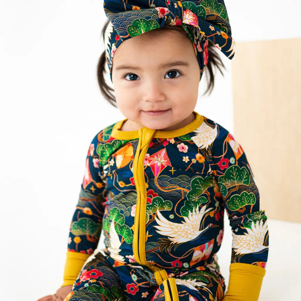 Child wearing a colorful outfit with a floral headband on a white background