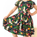 Child wearing a colorful dress with floral and crane patterns on a white background