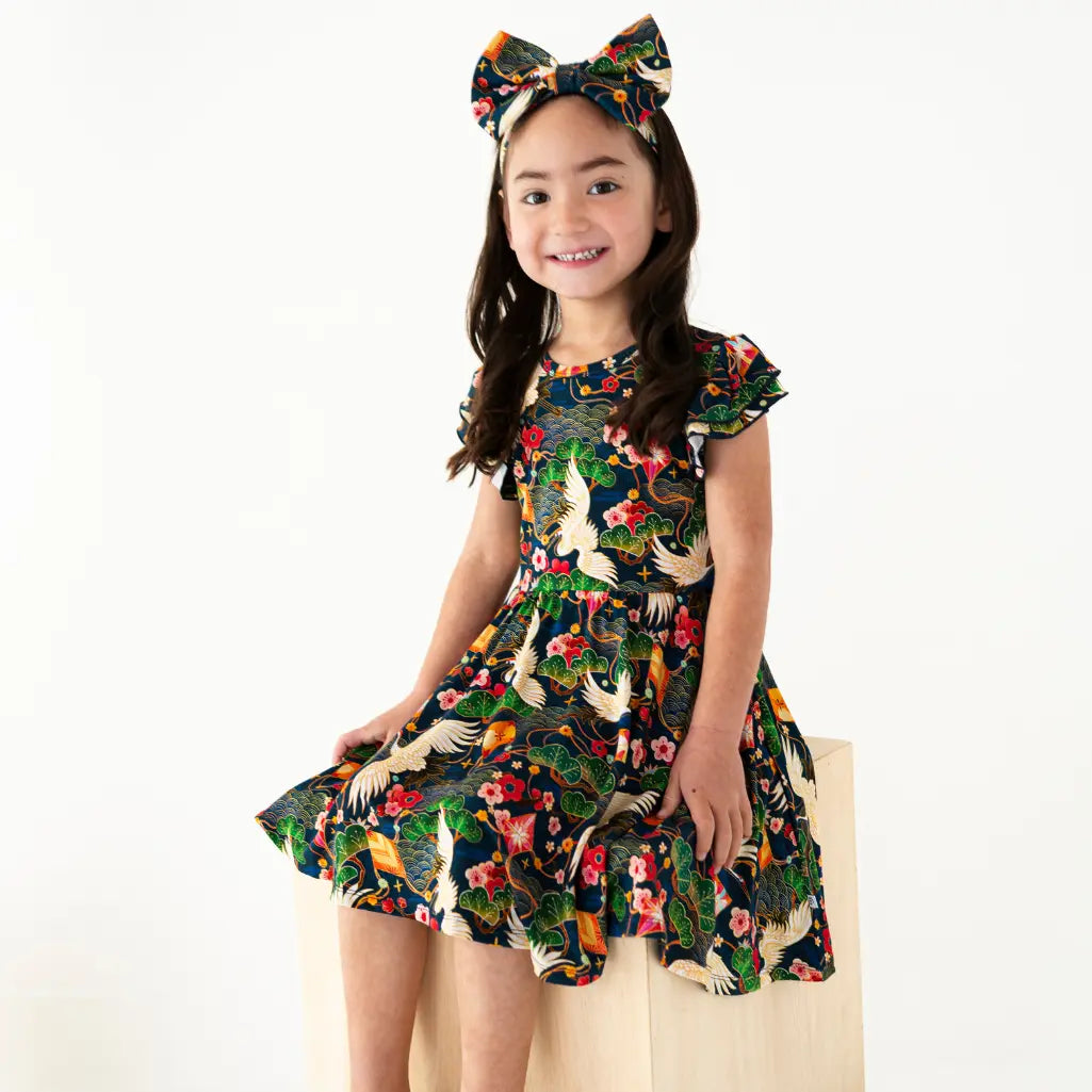 Young girl wearing a colorful dress with a floral and animal pattern on a white background