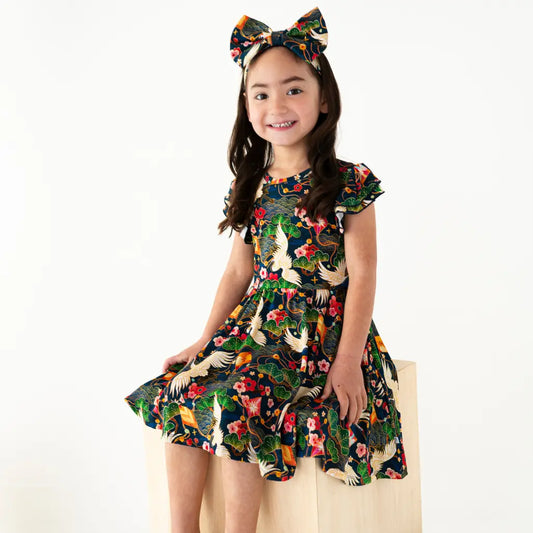 Young girl wearing a colorful dress with a floral and animal pattern on a white background