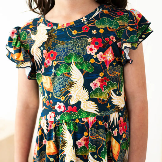 Child wearing a colorful dress with floral and bird patterns on a plain background