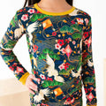 Person wearing a long-sleeve shirt with a colorful traditional pattern featuring cranes, flowers, and kites.