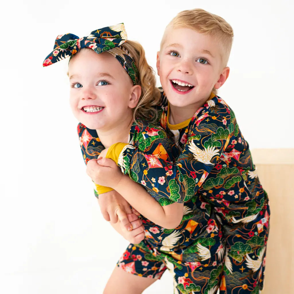 Two children wearing matching floral pajama sets on a white background
