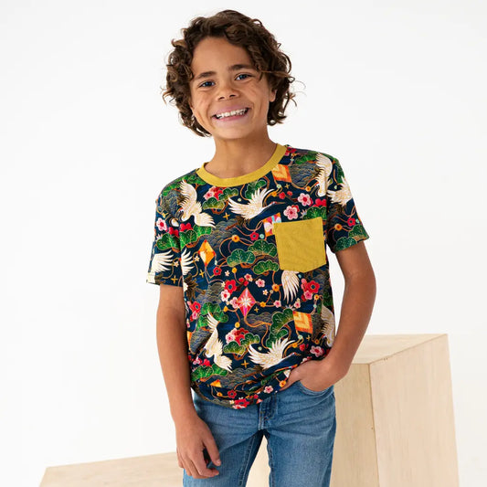 Child wearing a colorful patterned shirt with a yellow pocket on a white background