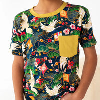 Person wearing a colorful t-shirt with floral and bird patterns on a white background