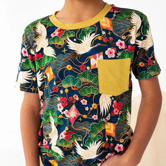 Person wearing a colorful t-shirt with floral and bird patterns on a white background