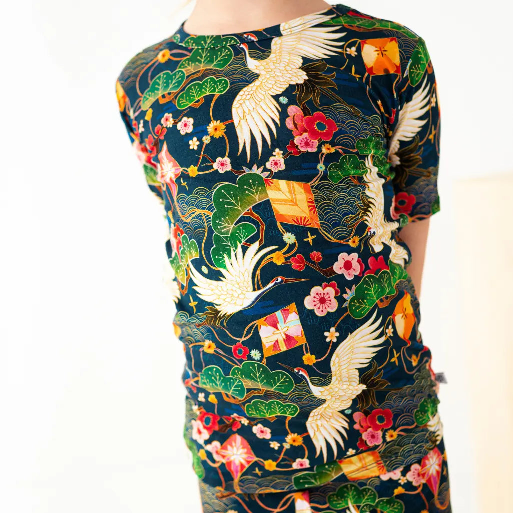 Colorful traditional patterned shirt with cranes and floral designs on a white background