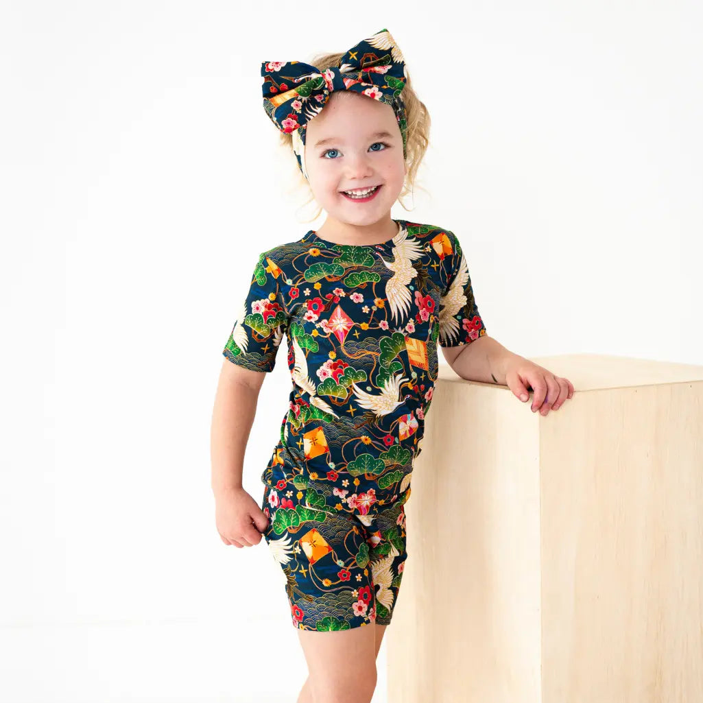 Child wearing a colorful dress with floral and animal patterns on a white background