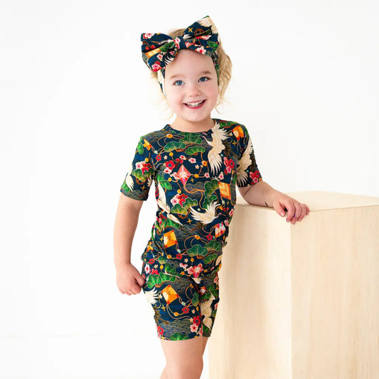 Child wearing a colorful dress with floral and animal patterns on a white background
