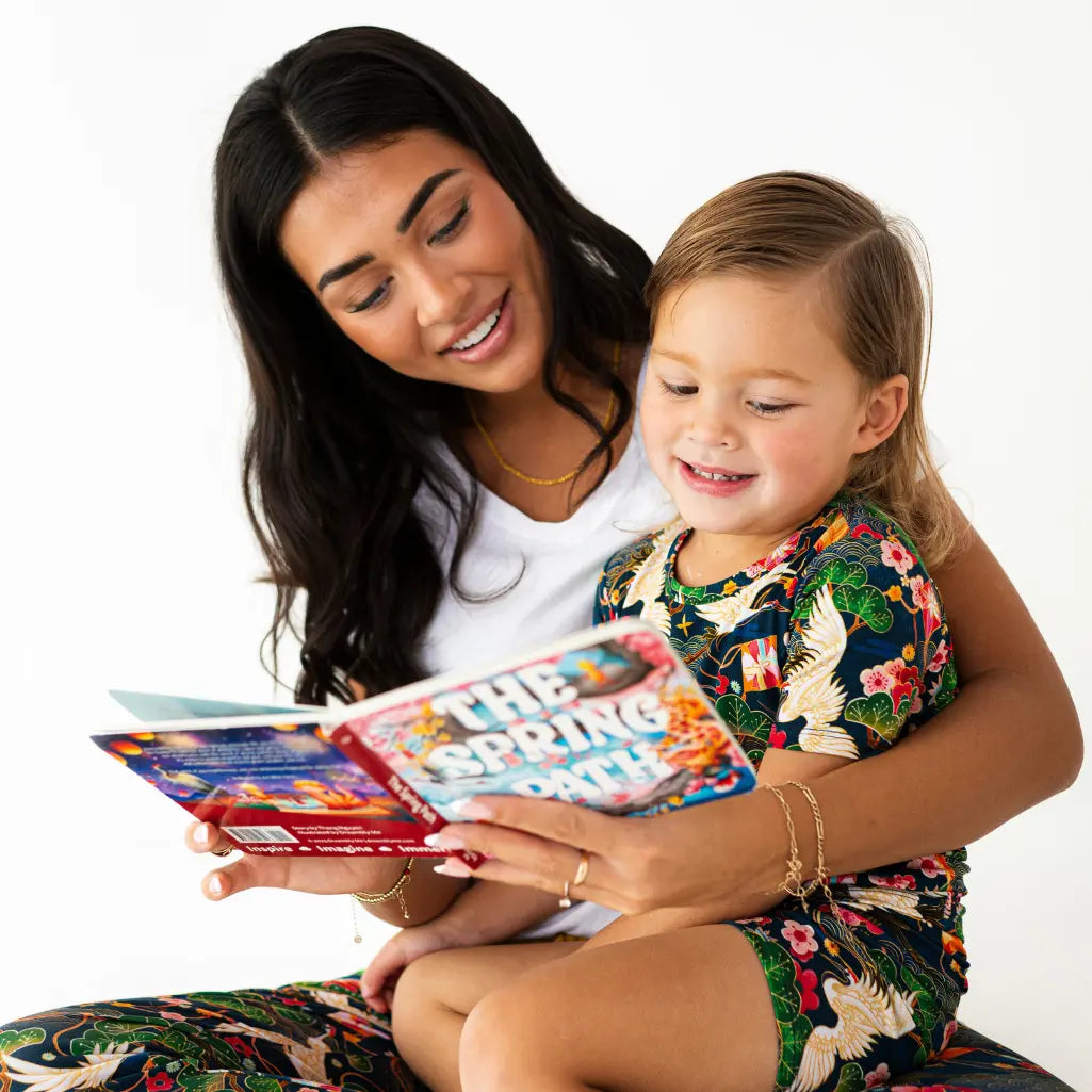Woman and child reading a book together on a white background