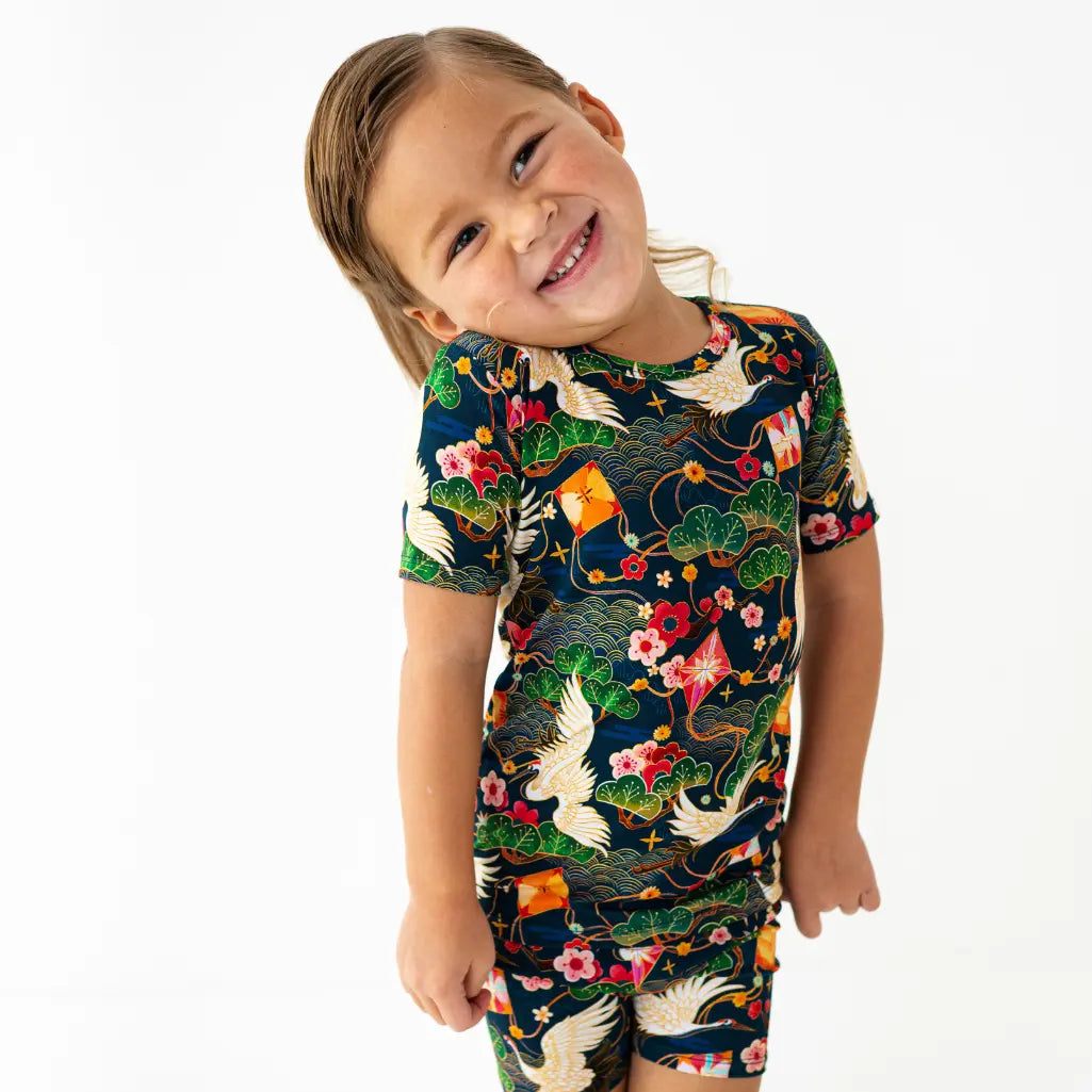 Child wearing a colorful floral and bird patterned outfit on a white background