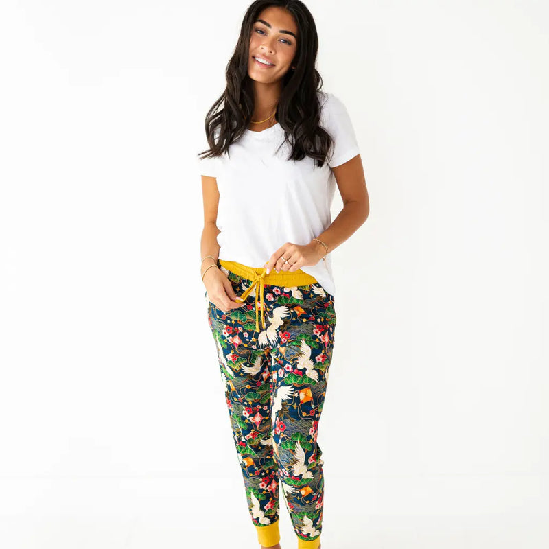 Woman wearing a white t-shirt and colorful floral pajama pants with yellow drawstring on a white background
