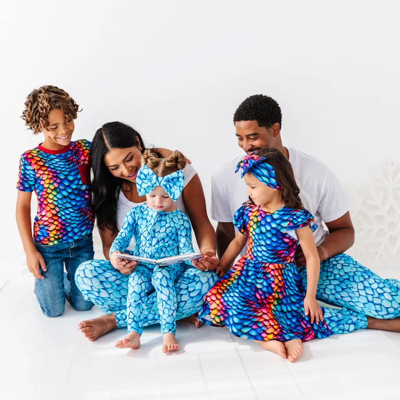 Family of four wearing colorful dragon-themed clothing on a white background